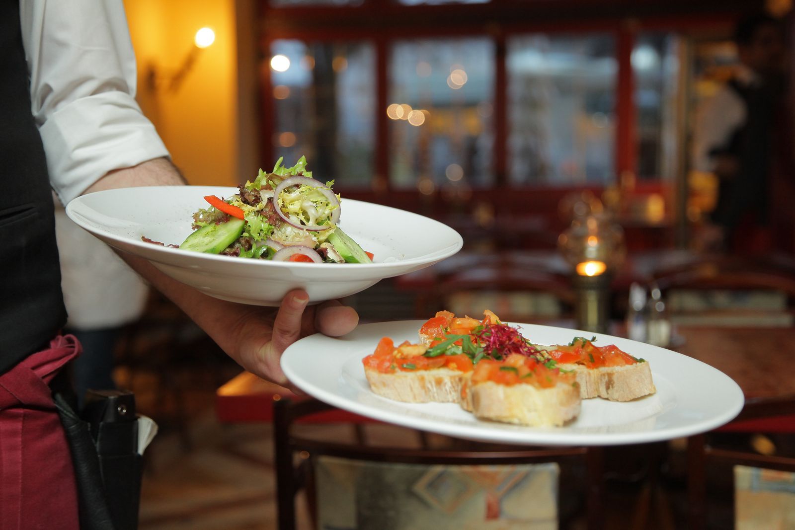 Restaurant server presenting plated dishes